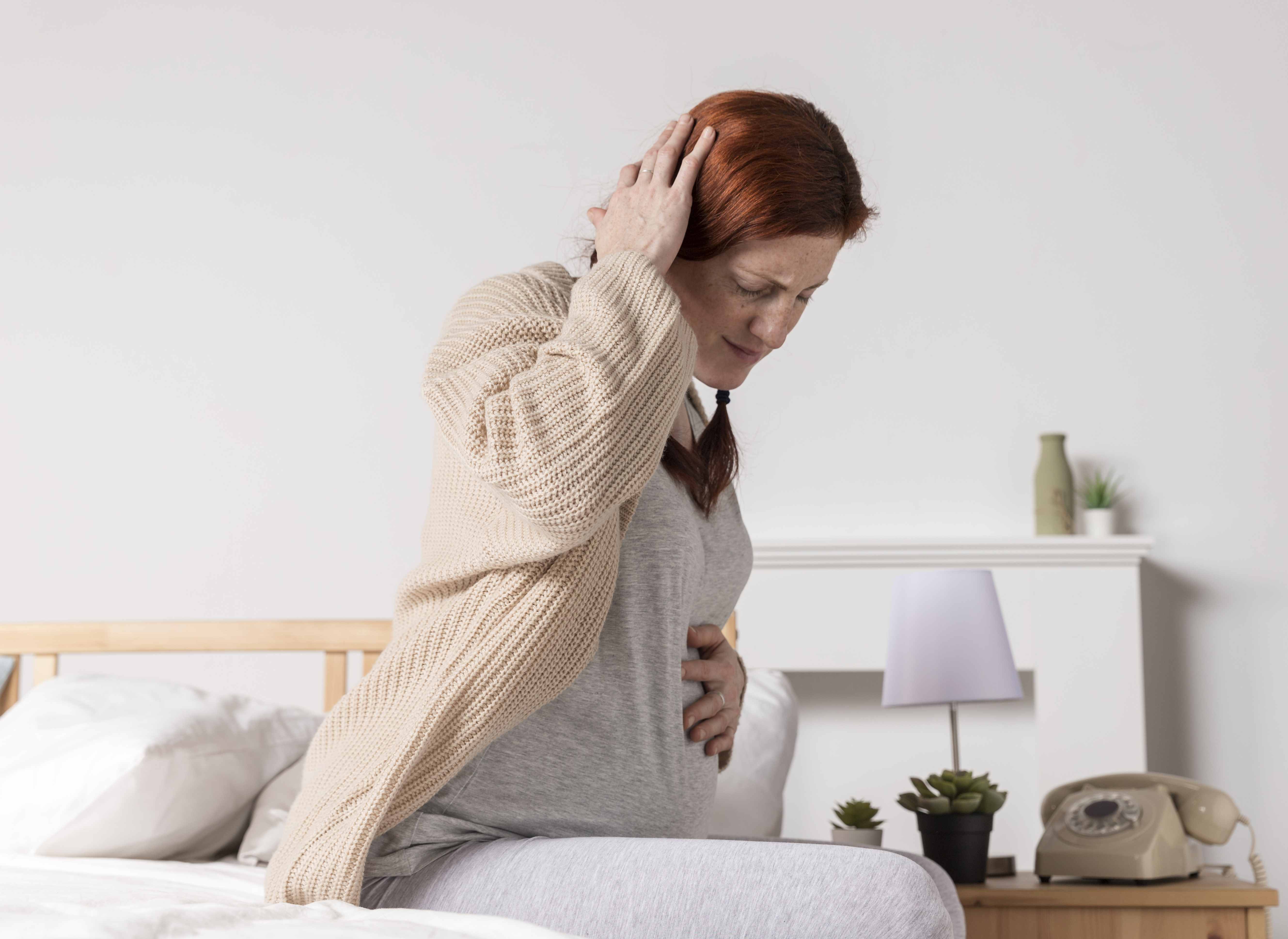 Pregnant woman experiencing lower back pain and headache during pregnancy